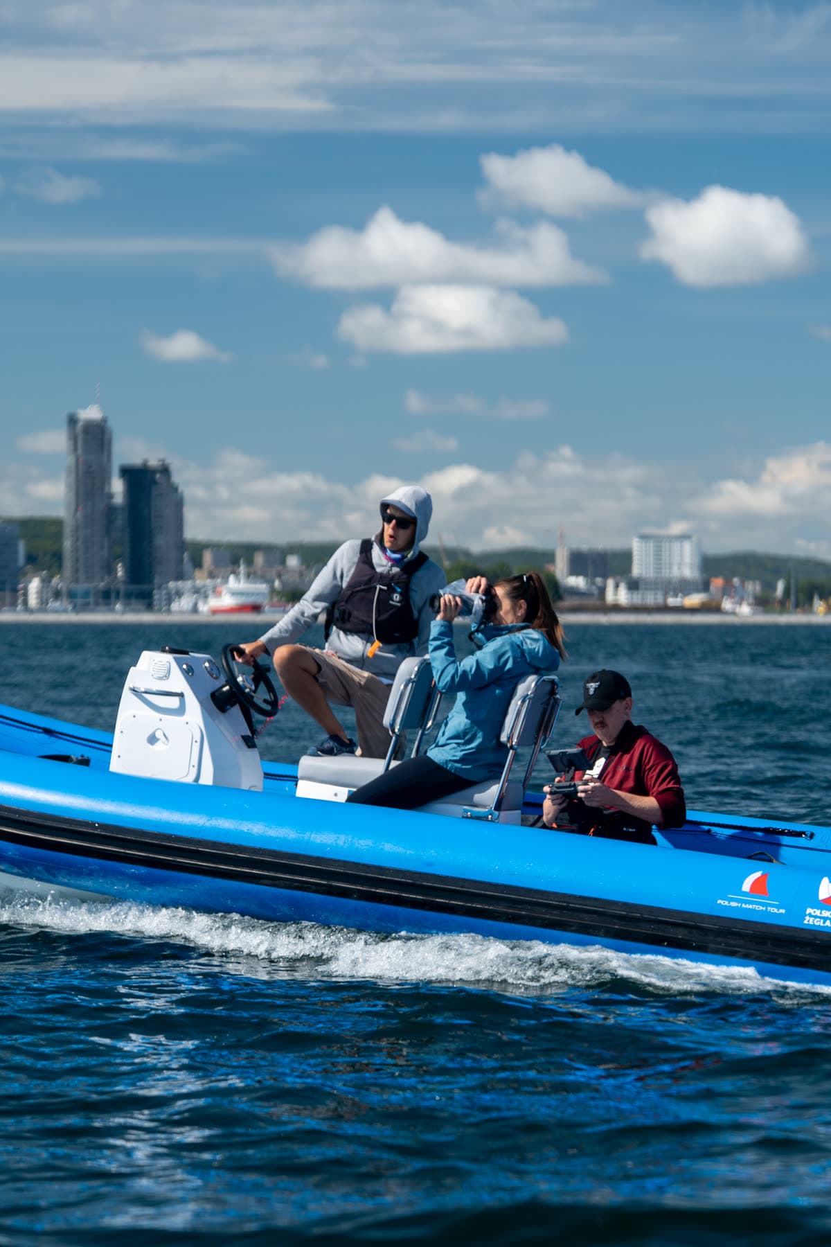Ekipa Przelot Studio na motorówce — pilot drona z kontrolerem, w tle Gdynia